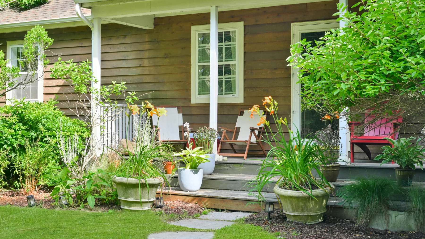 A wooden house porch with outdoor seating and potted plants.