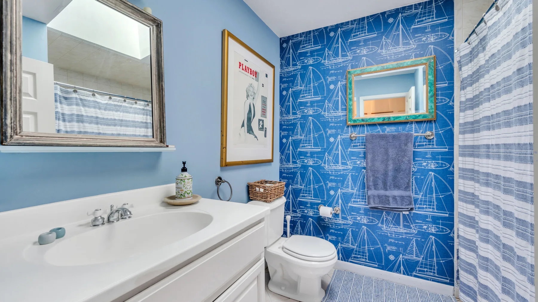 A bathroom with a sink, toilet, and blue patterned walls.
