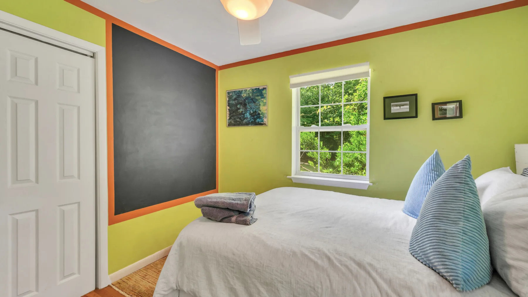A bedroom with a bed, a window, and a large dark wall panel.