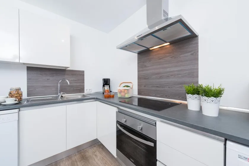 A modern kitchen with white cabinets, a cooktop, and a countertop.