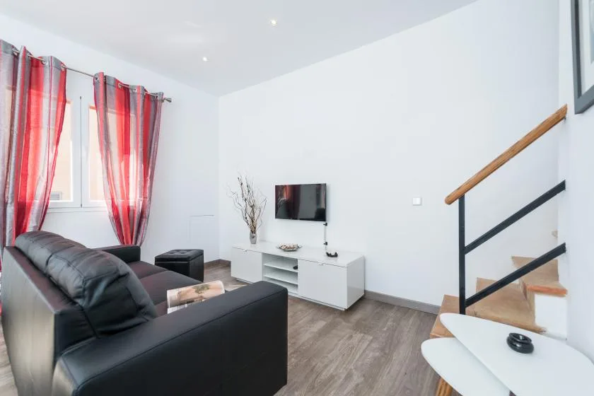 A bright living room with seating, a television, and stairs.