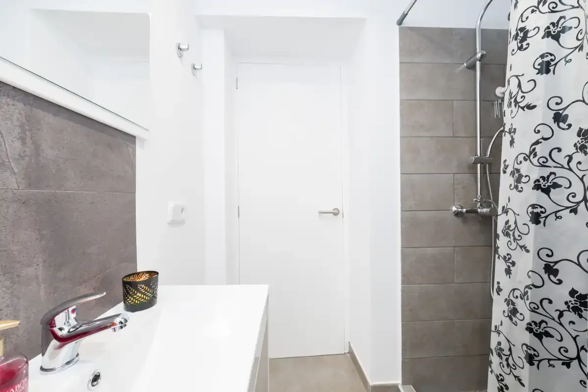 A bright bathroom with a sink and a patterned shower curtain.