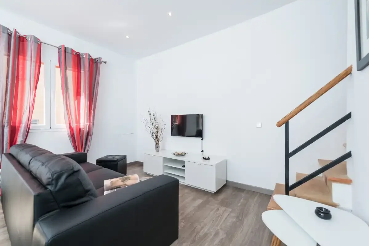 A living room with seating, a television, and a staircase.