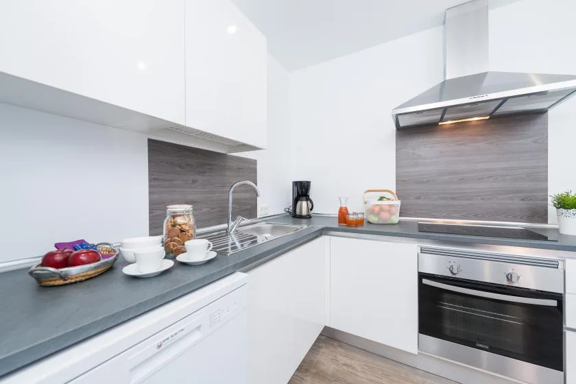 A modern kitchen with white cabinets, a countertop, and a stainless steel oven.