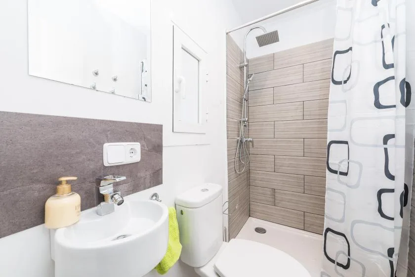 A bathroom with a sink and a shower behind a patterned curtain.