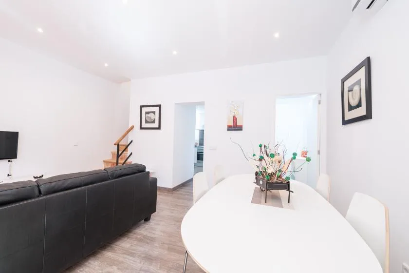 A bright dining area with a white table beside a living room seating area.