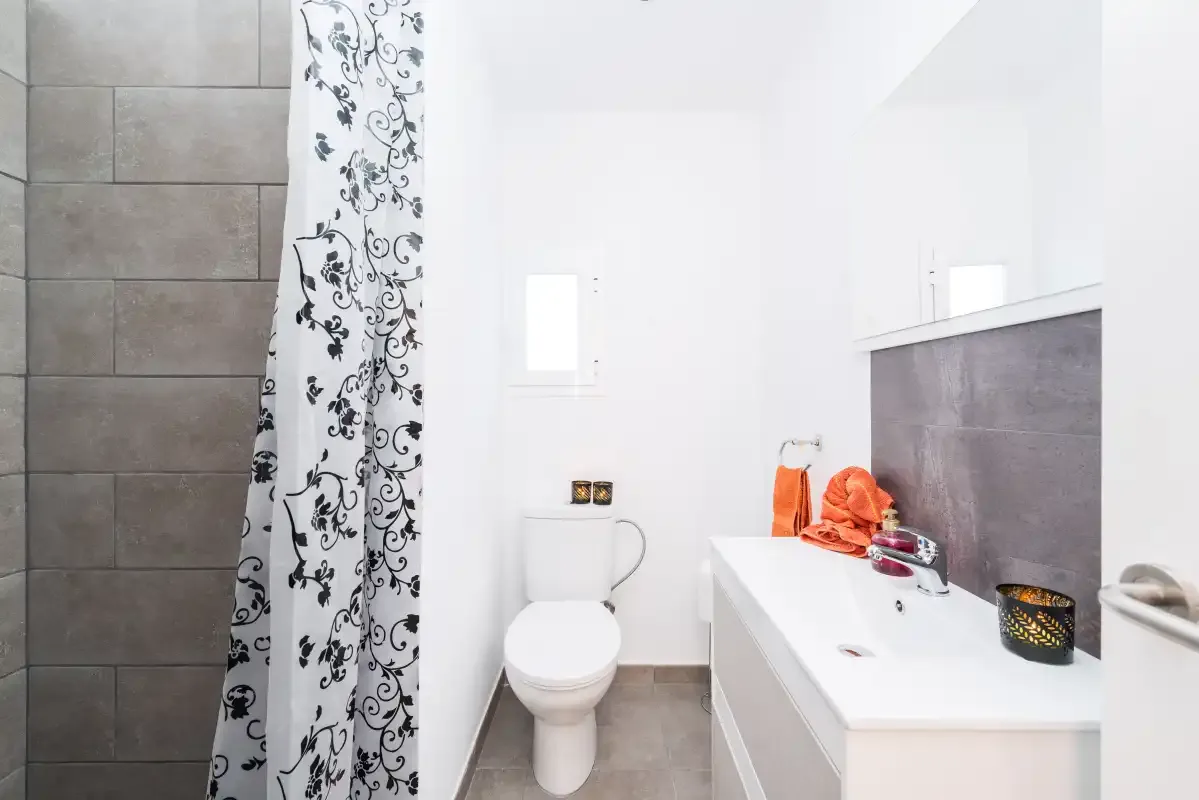 A bright bathroom with a toilet, sink, and patterned shower curtain.