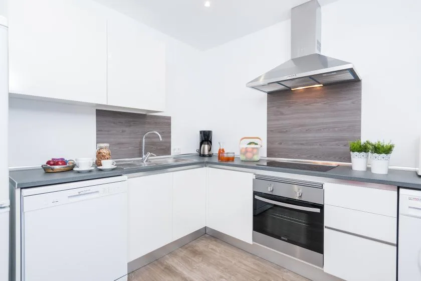 A bright modern kitchen with white cabinets, a countertop, and an oven.