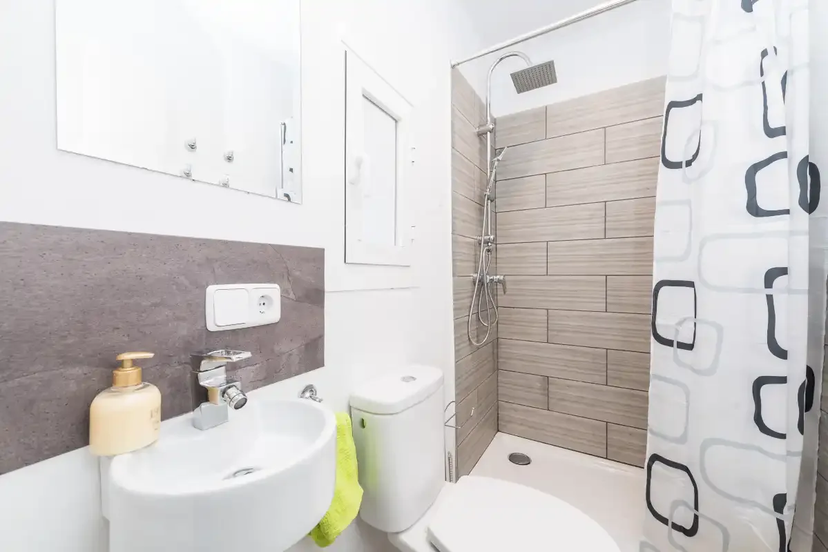 A bathroom with a sink, toilet, and shower behind a patterned curtain.