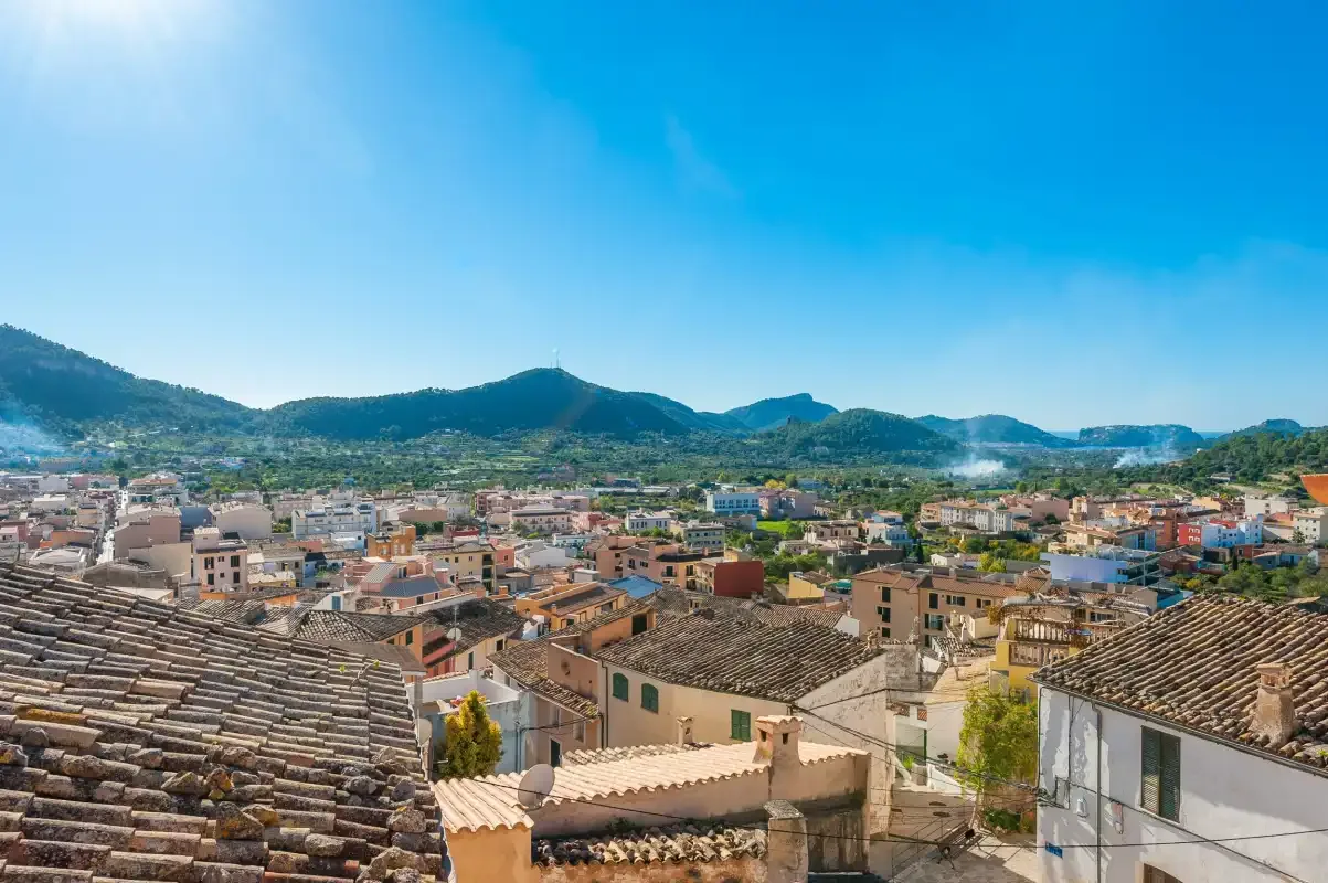 A town spreads across the foreground beneath a range of green hills.