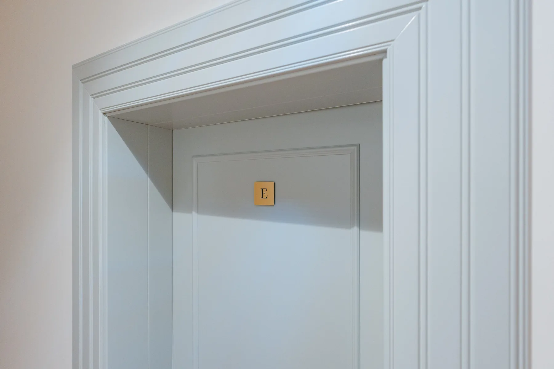 Una puerta blanca está enmarcada por molduras blancas decorativas.