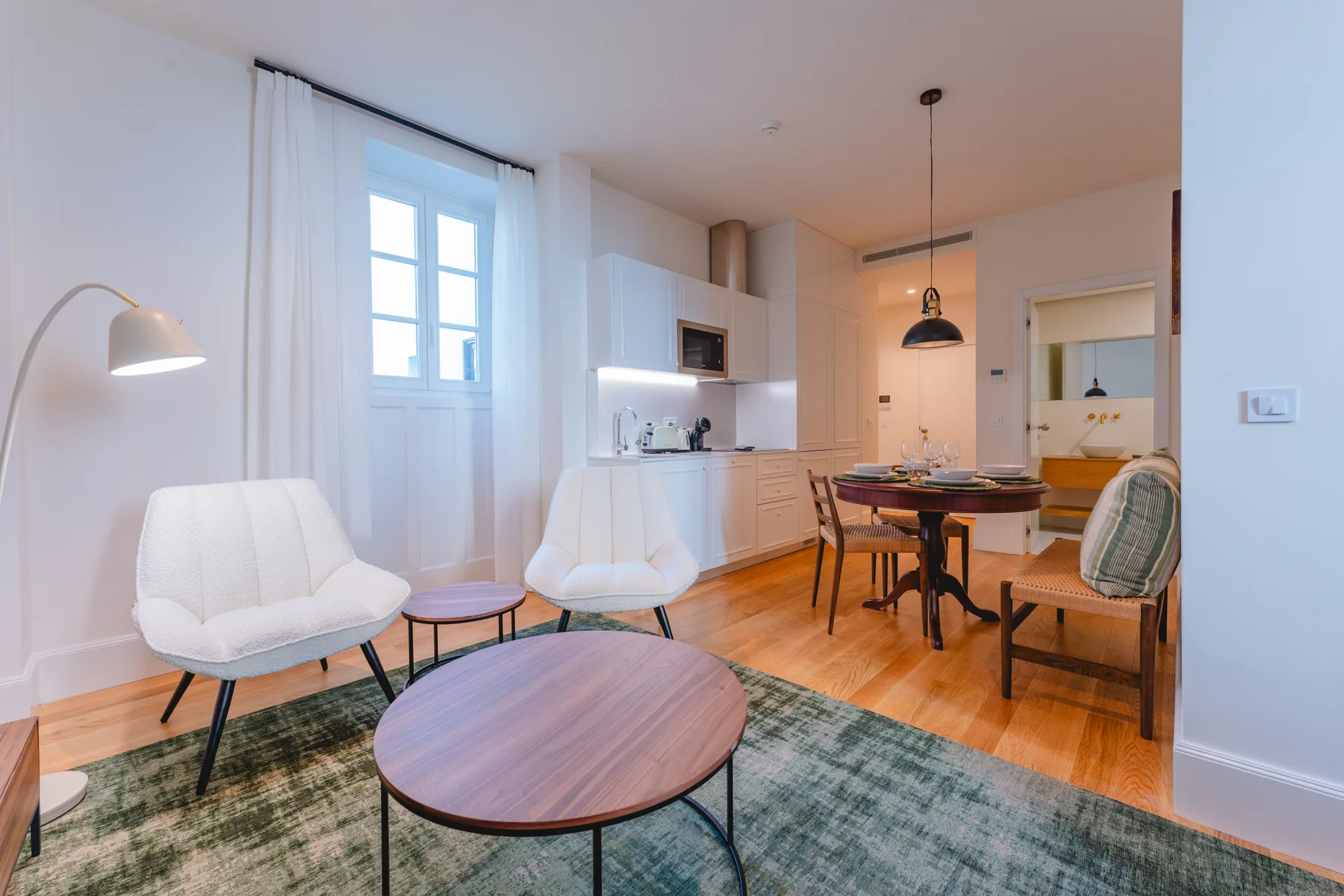 Una sala-comedor de planta abierta con cocina, asientos y suelo de madera.