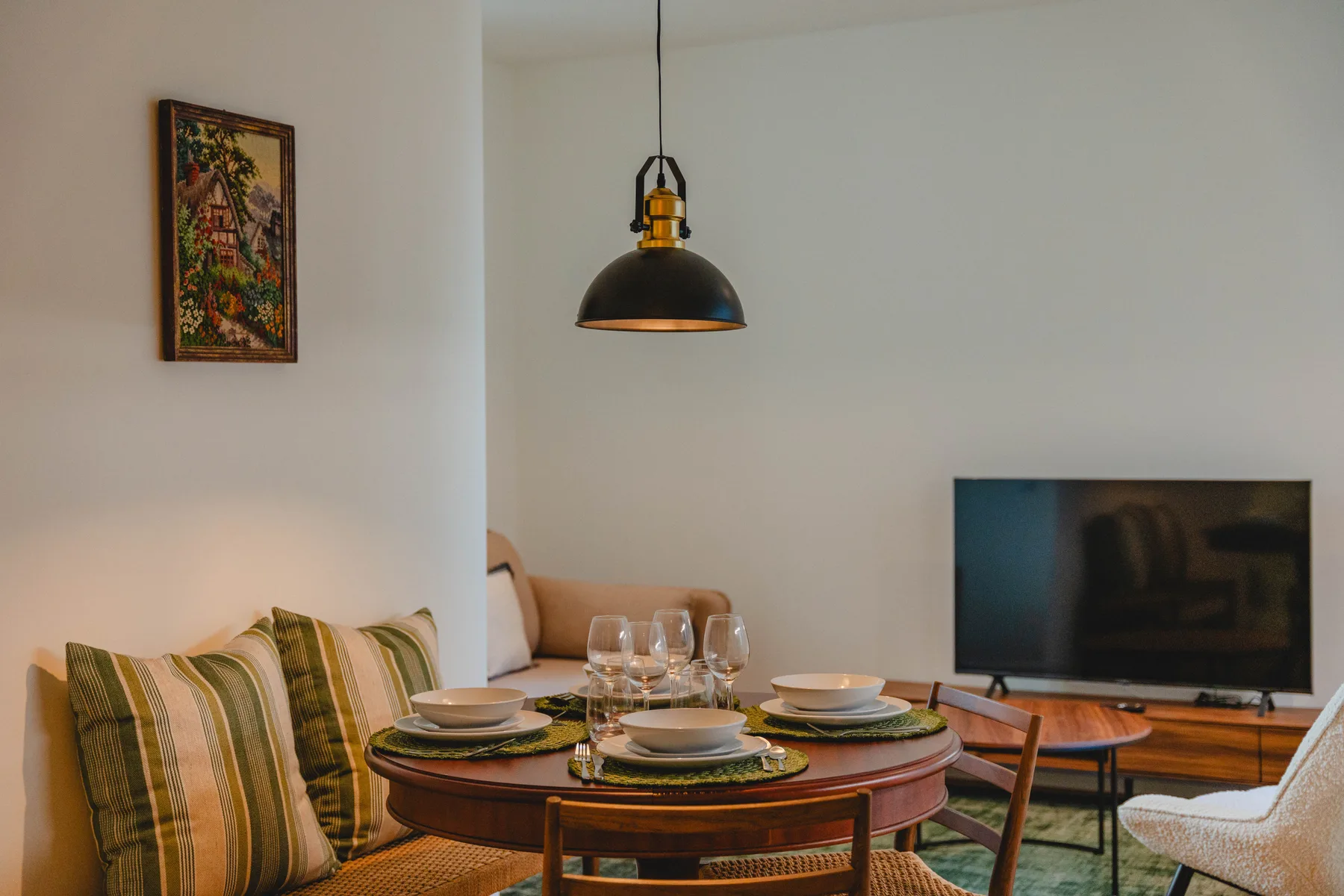 Comedor con la mesa puesta, cojines a rayas y un televisor.