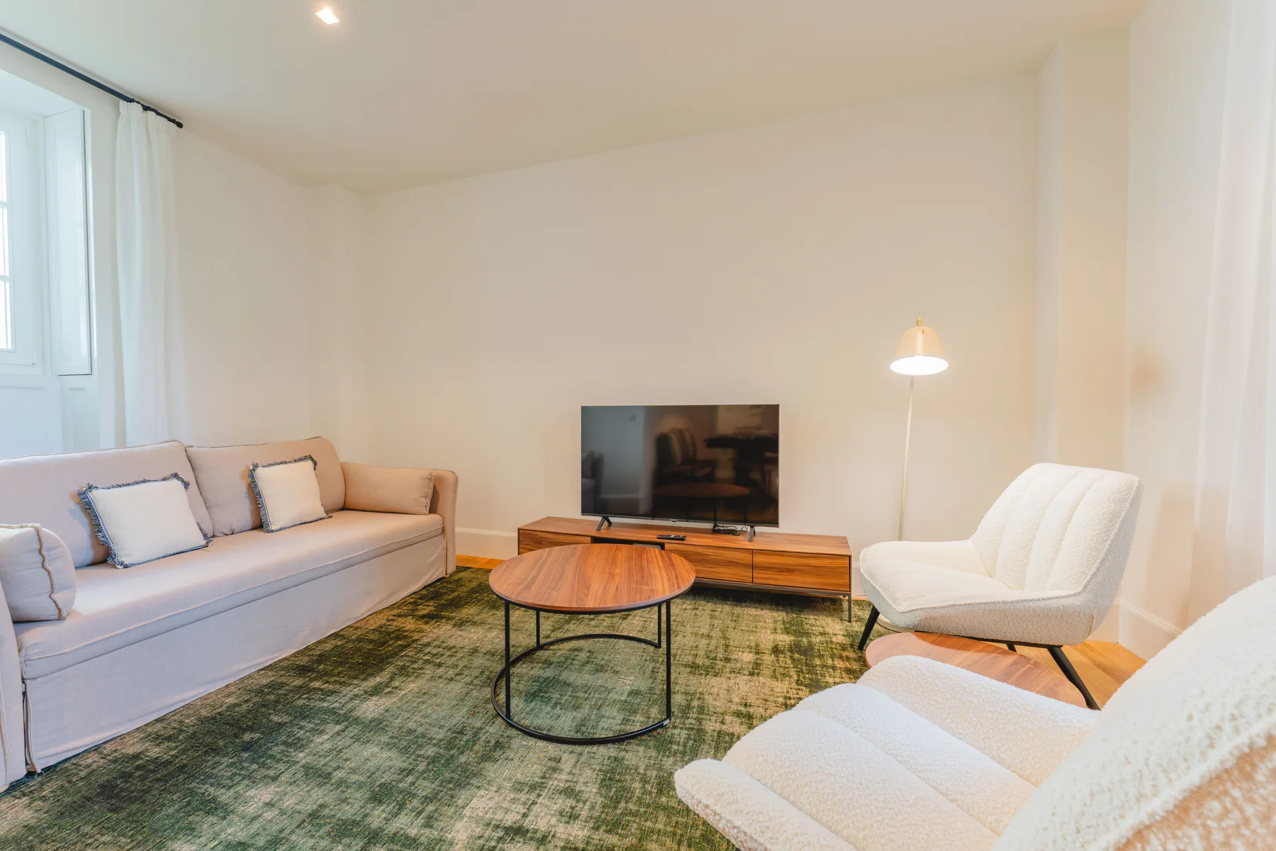 Una sala de estar con asientos, un televisor y una mesa de centro.