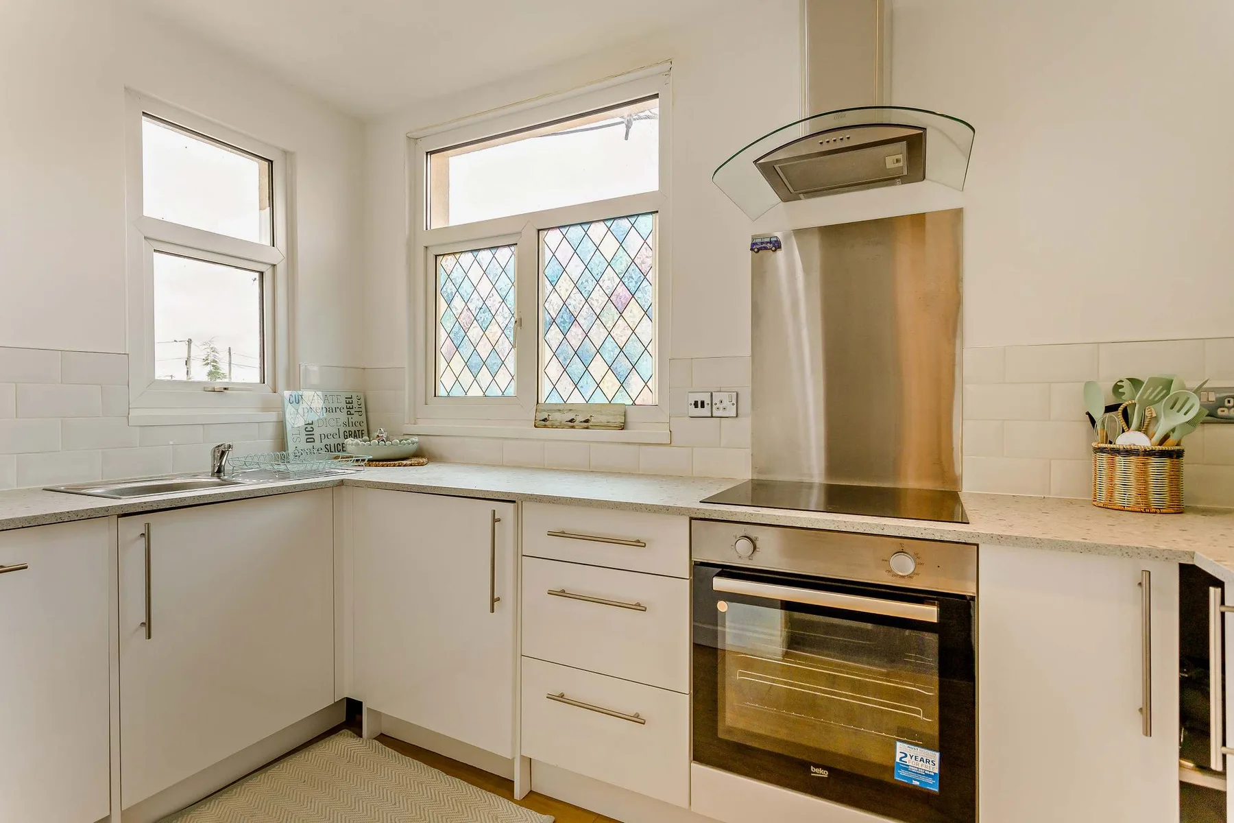 A bright kitchen with white cabinetry, a countertop, and a built-in oven.