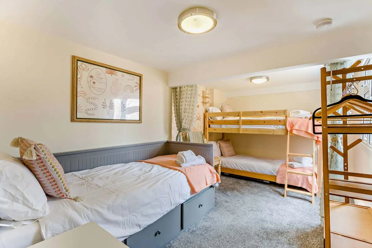 Un dormitorio con una cama grande y literas de madera.