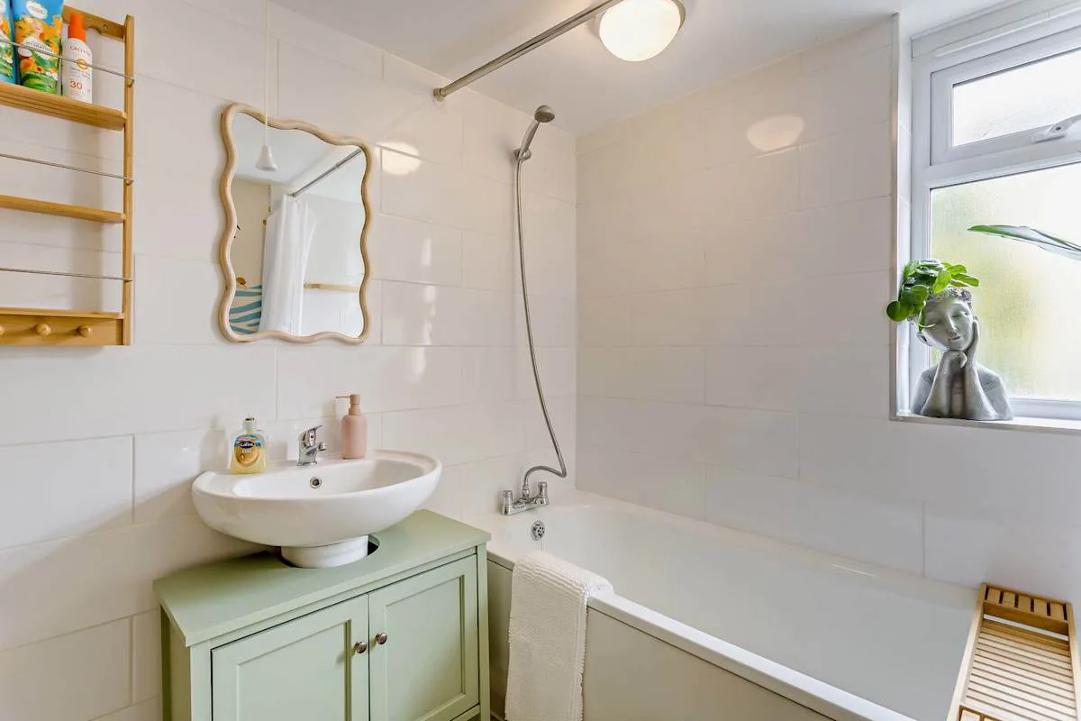 Un baño luminoso con lavabo, espejo y bañera.