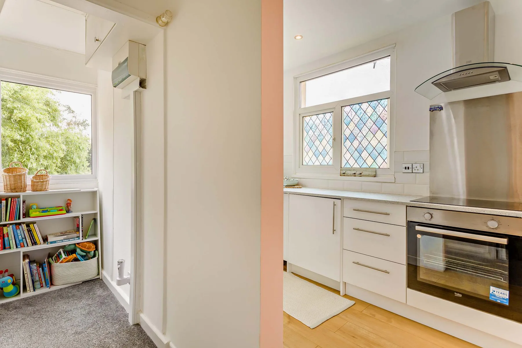 Una cocina luminosa con armarios blancos, una ventana y un horno.