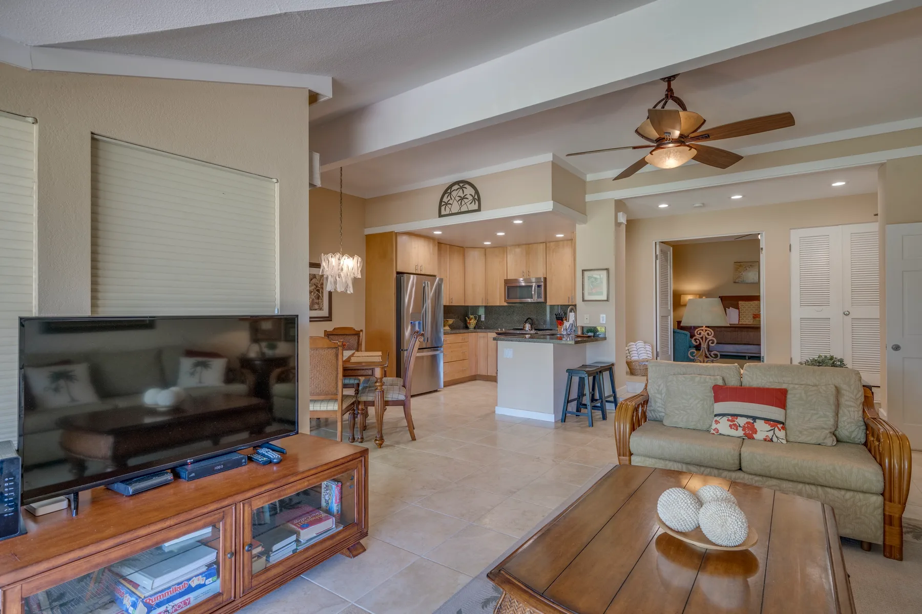 Una sala de estar se abre a una cocina, con un televisor y una zona de asientos.