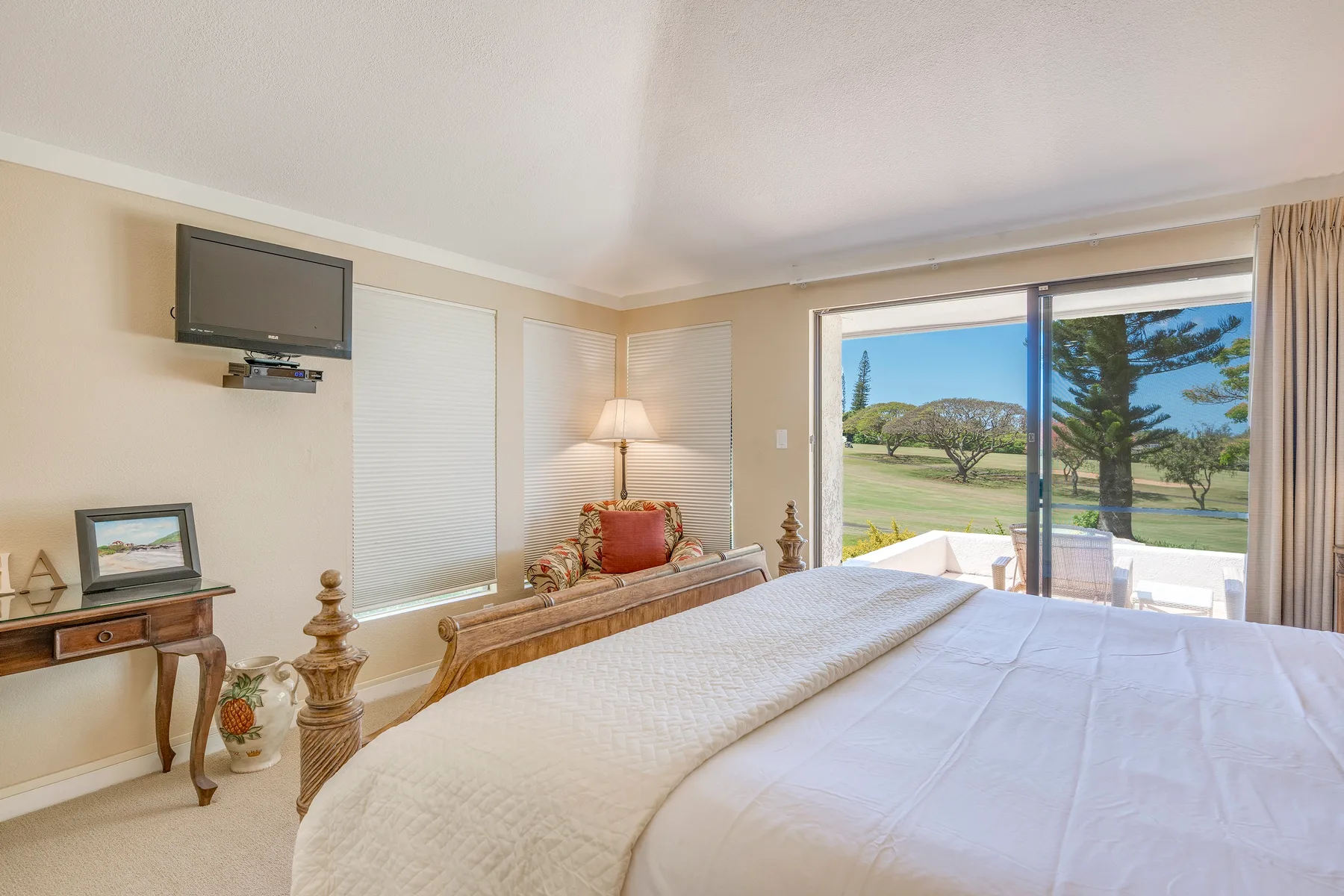 Un dormitorio luminoso con una cama grande y puertas corredizas de vidrio que dan a un patio.