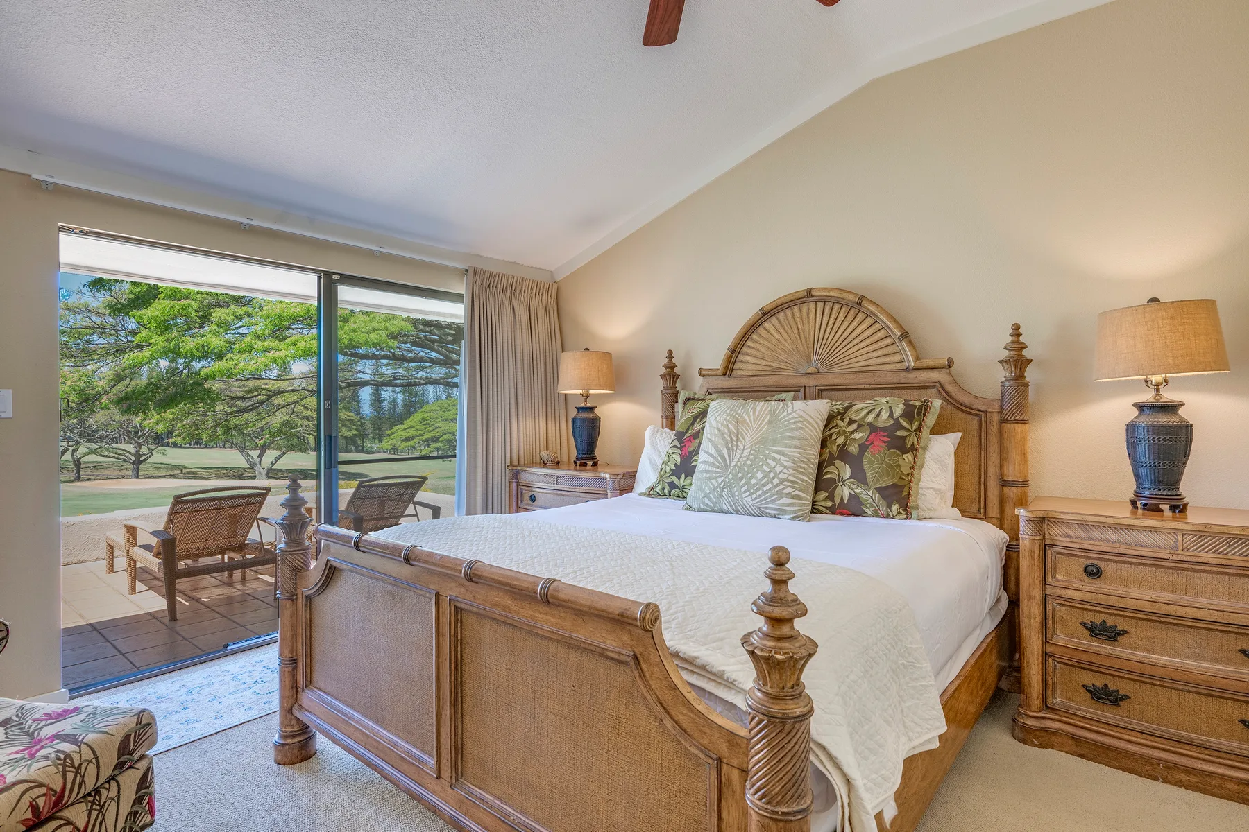 Un dormitorio con cama de madera, mesitas de noche y puertas corredizas de vidrio que dan a un patio.