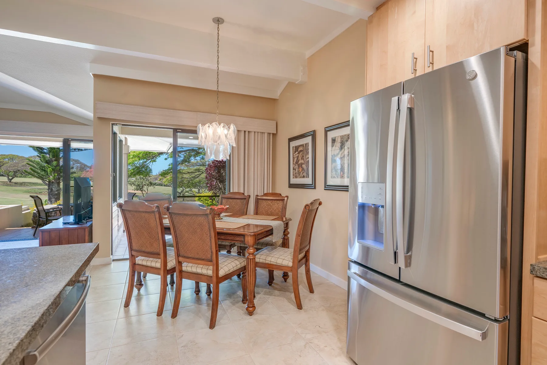 Comedor con una mesa de madera y asientos junto a un refrigerador de acero inoxidable.