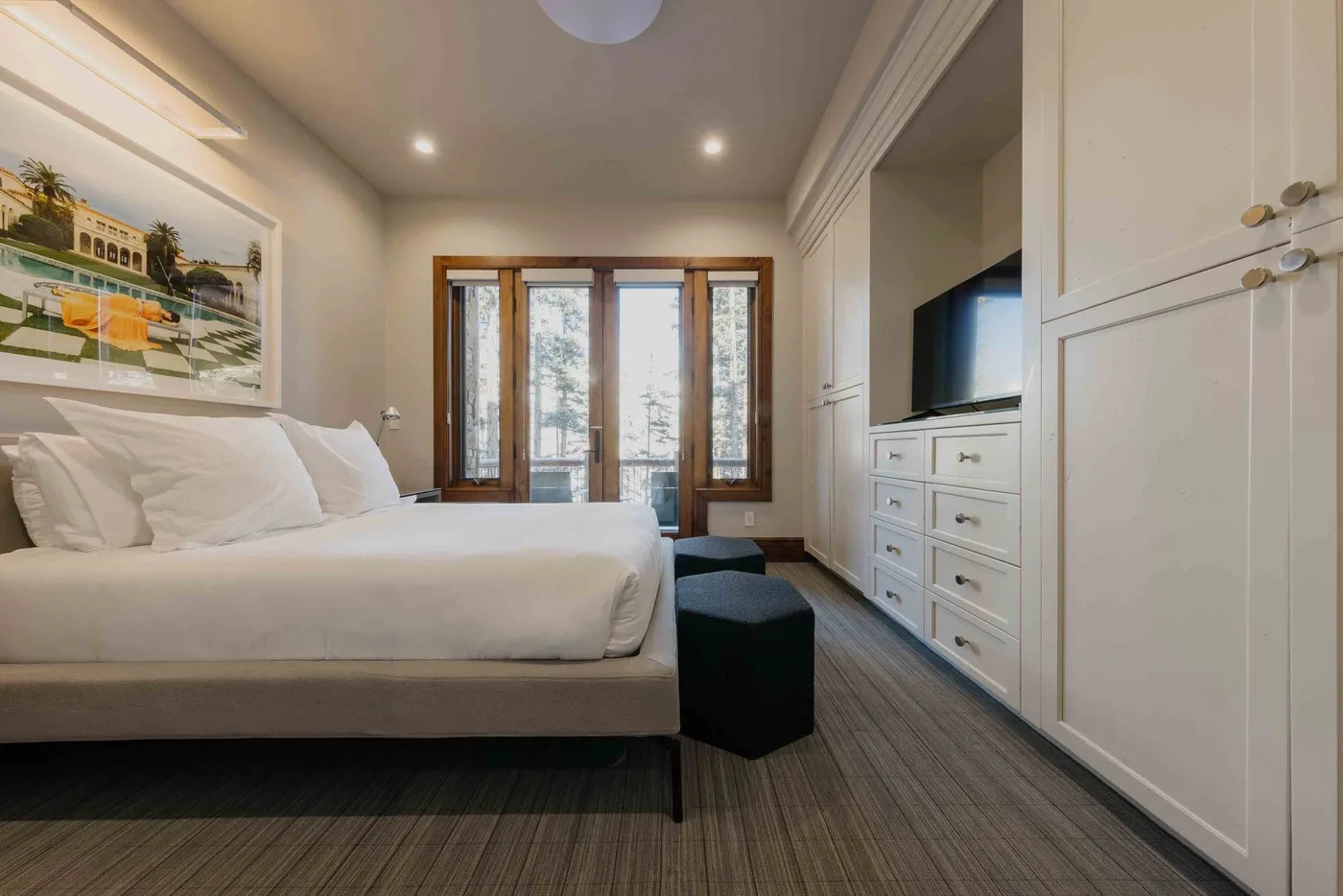 A bedroom with a bed, built-in cabinetry, and glass doors opening to a balcony.