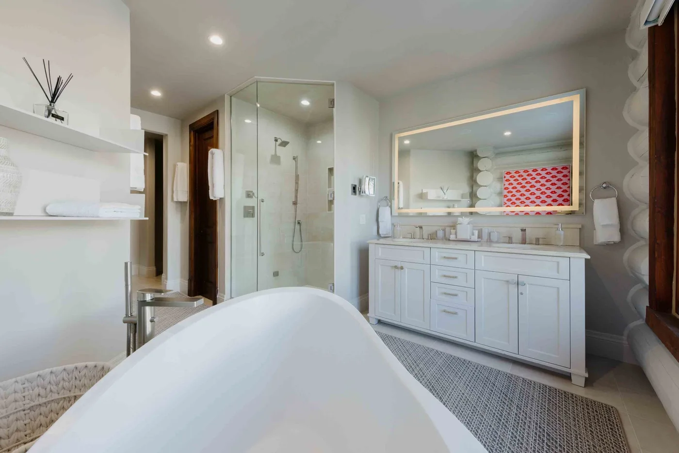 A bright bathroom with a freestanding bathtub, glass shower, and long vanity.