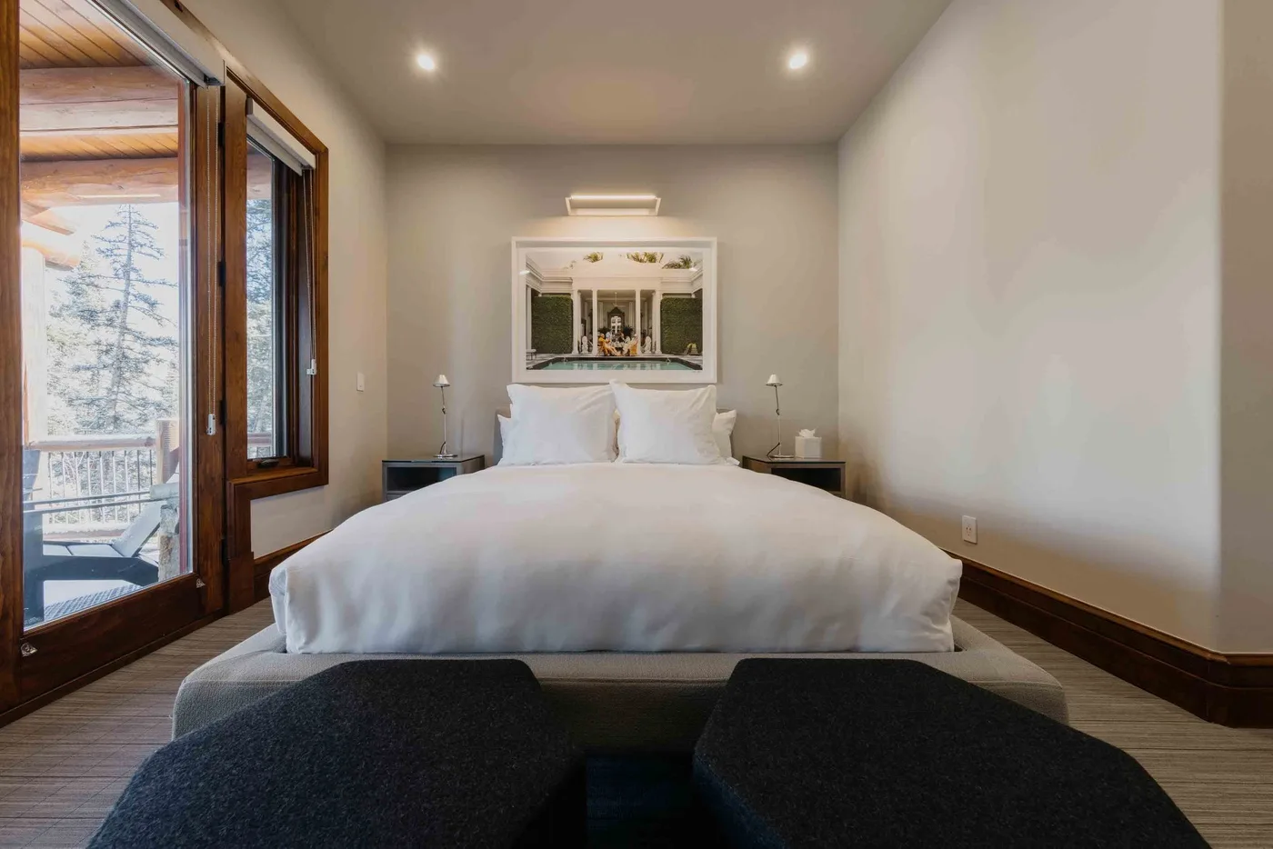 A bright bedroom with a neatly made bed and glass doors opening onto a balcony.