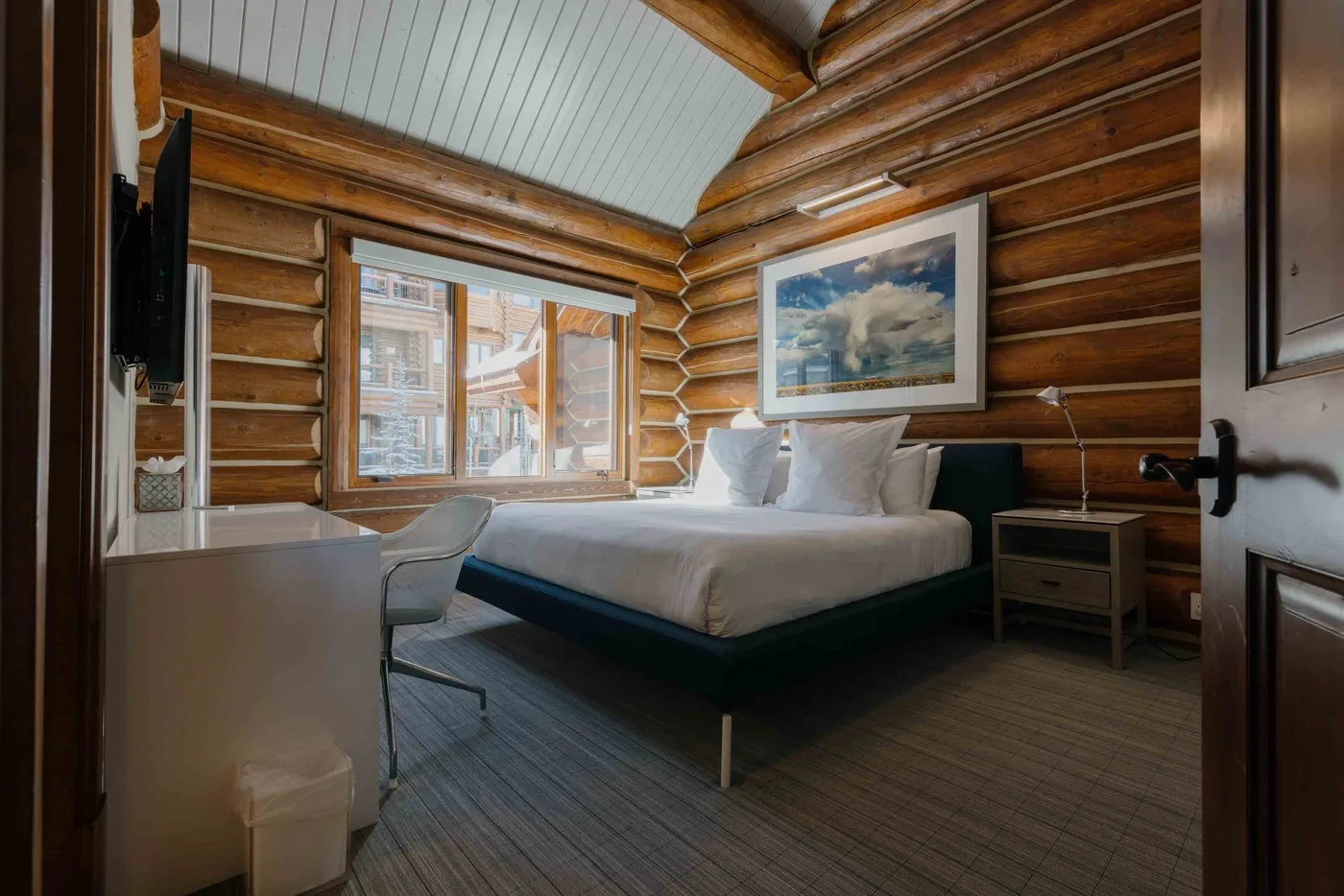A bedroom with a bed, window, and wood-paneled walls.