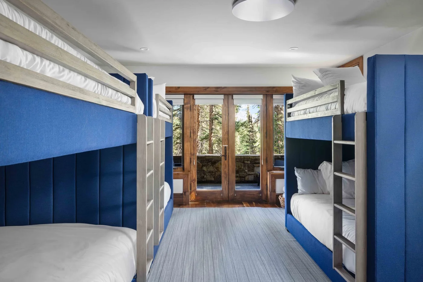 A bedroom with blue bunk beds and glass doors opening onto a balcony.