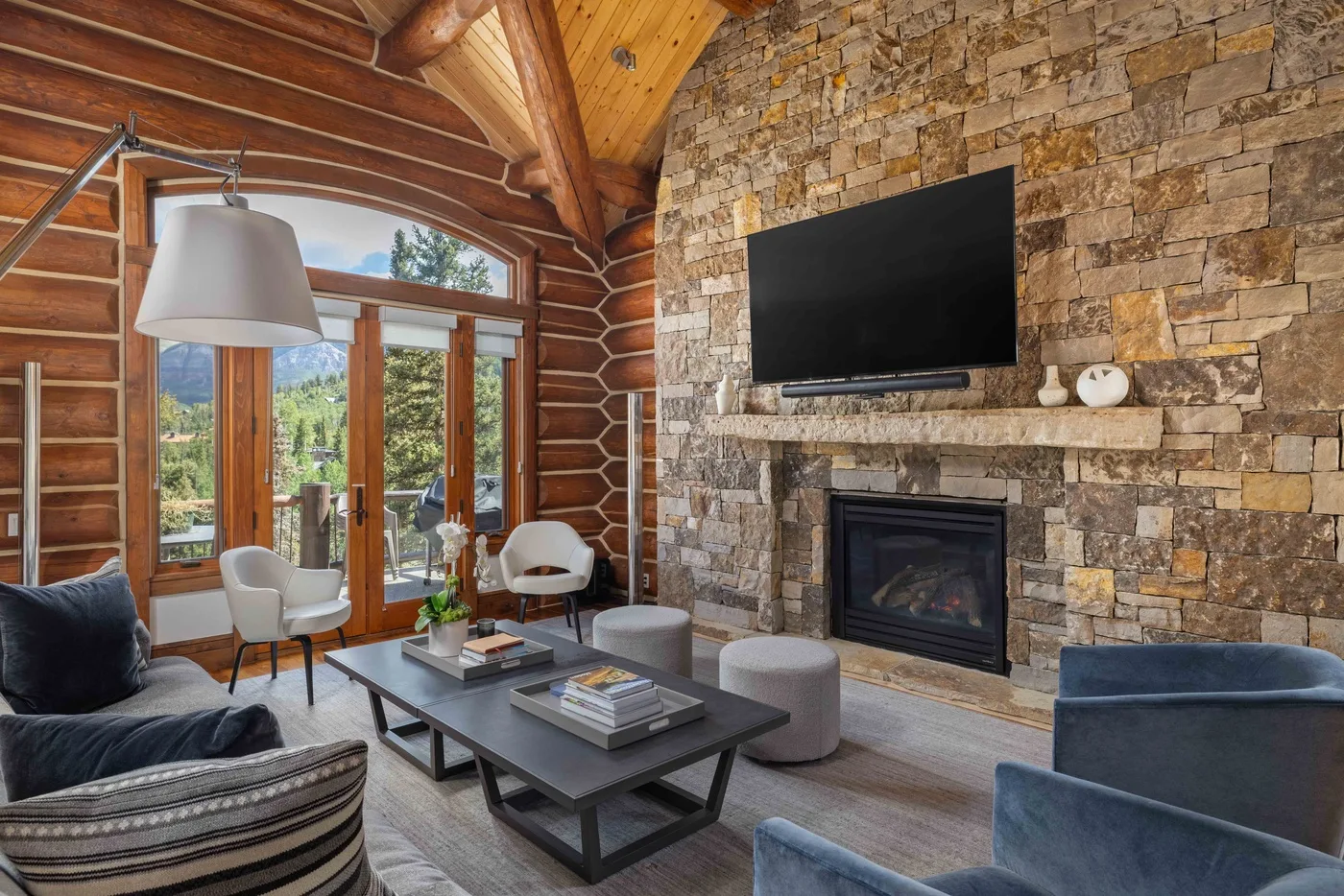 A rustic living room with seating arranged around a coffee table and fireplace.