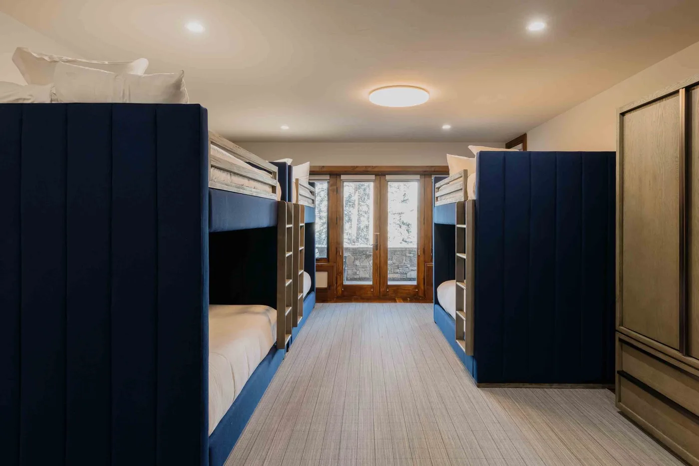 A dormitory bedroom with bunk beds arranged along both sides of a central aisle.