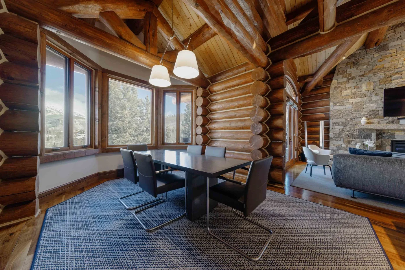 A dining area with a dark table and seating beneath exposed timber beams.