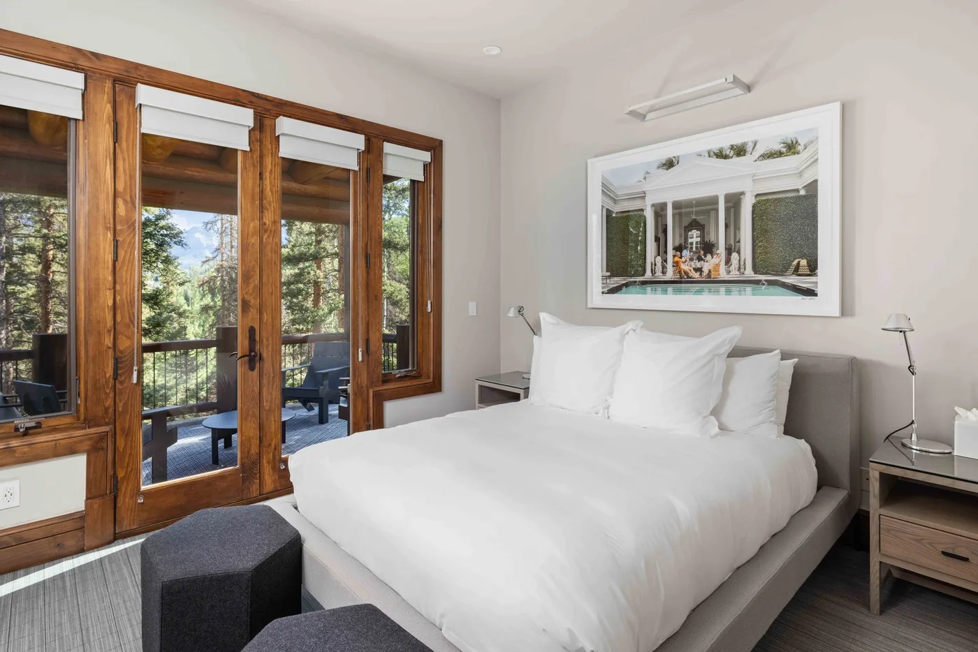 A bedroom with a large bed beside wood-framed glass doors.