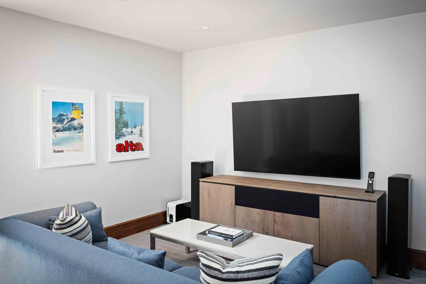 A living room with a large television above a console and seating.