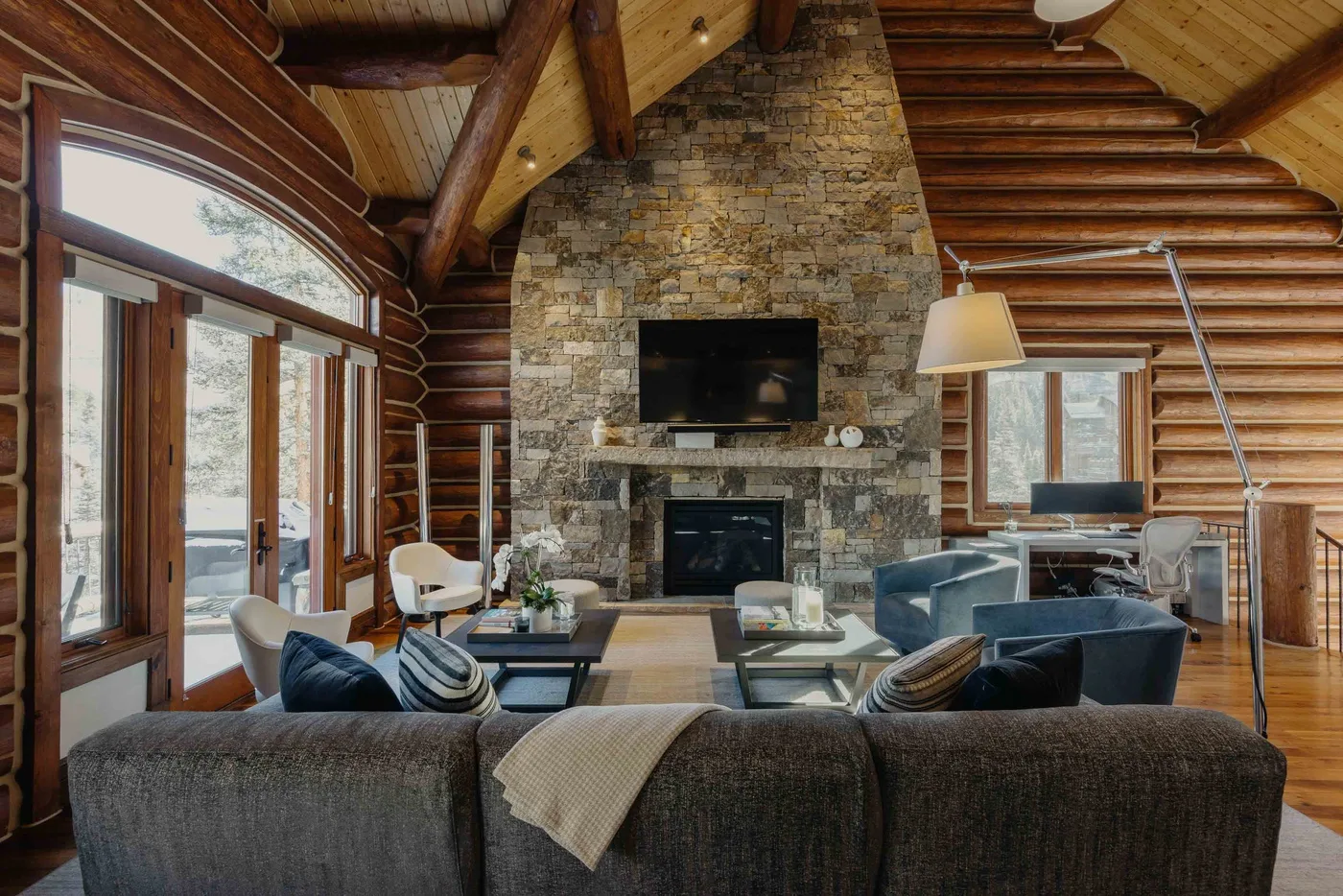 A log-walled living room with a stone fireplace and seating.