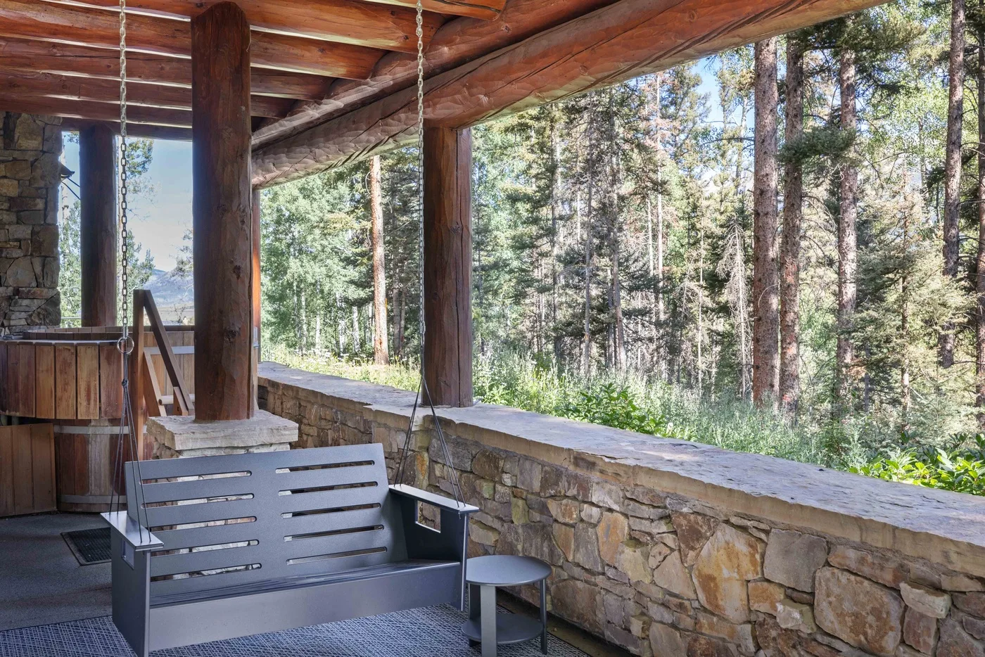 A covered outdoor seating area overlooks a wooded landscape.