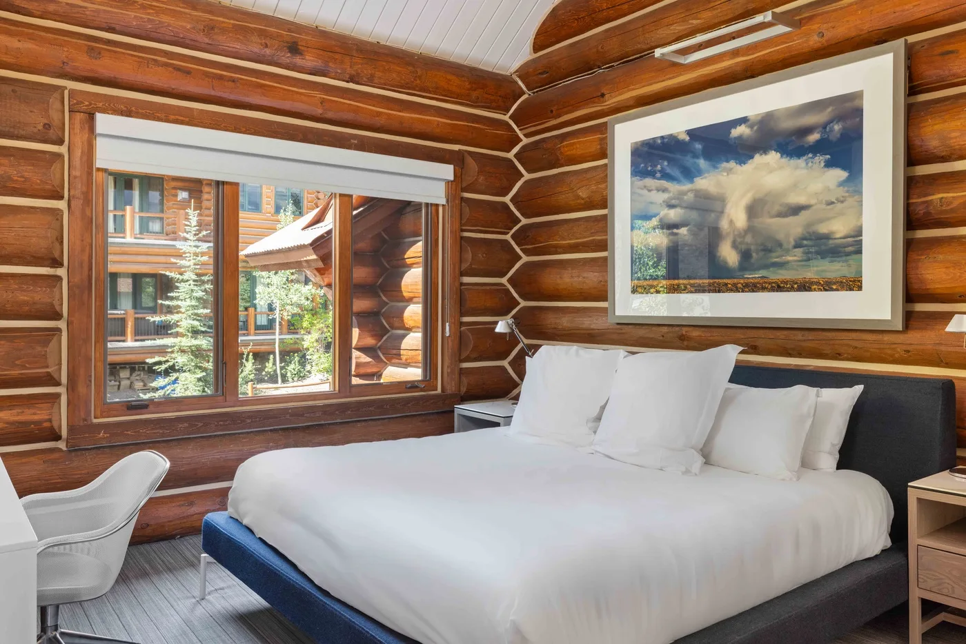 A bedroom with a large bed, windows, and wood-paneled walls.
