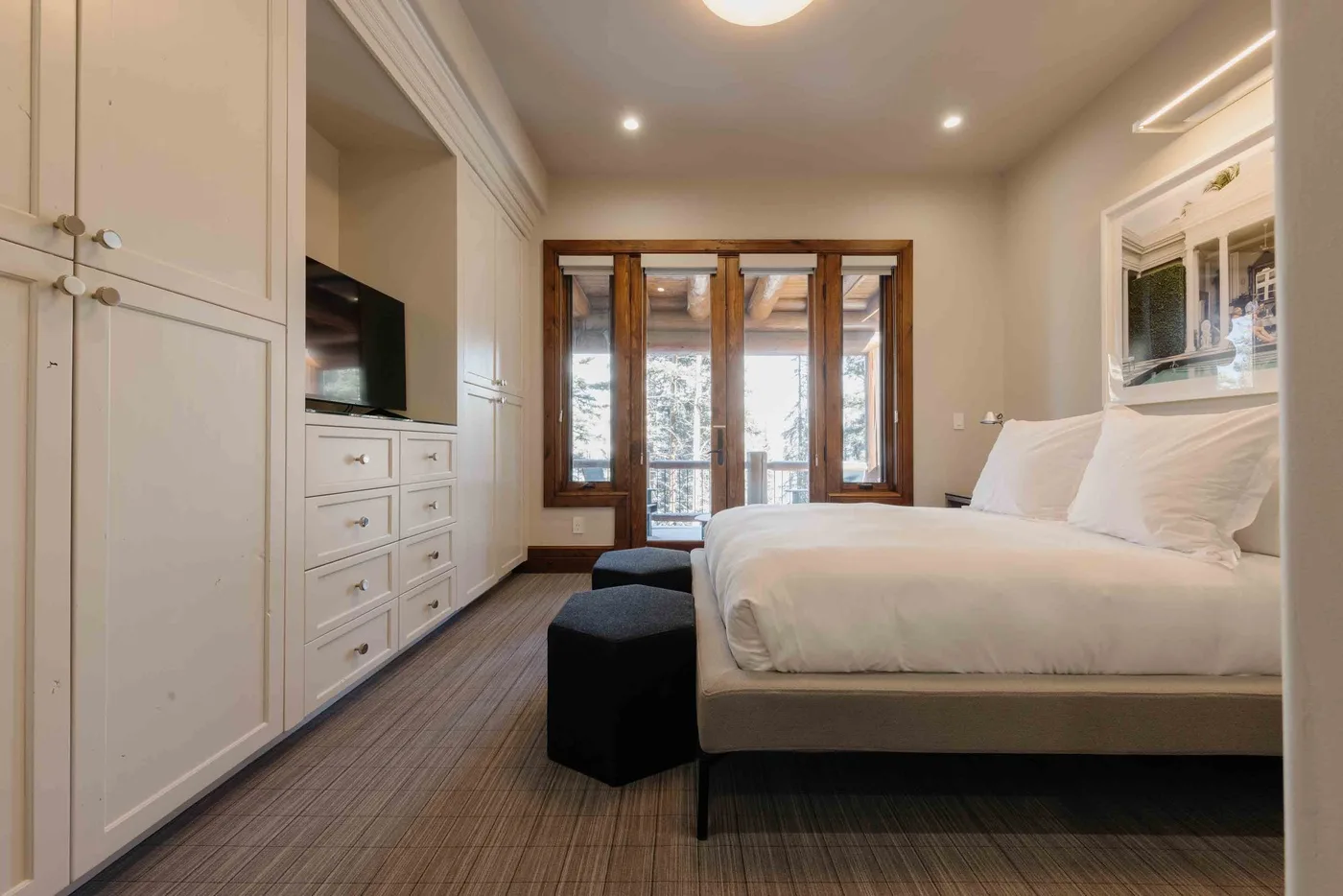 A bedroom with a bed, built-in cabinets, and glass doors opening onto a balcony.