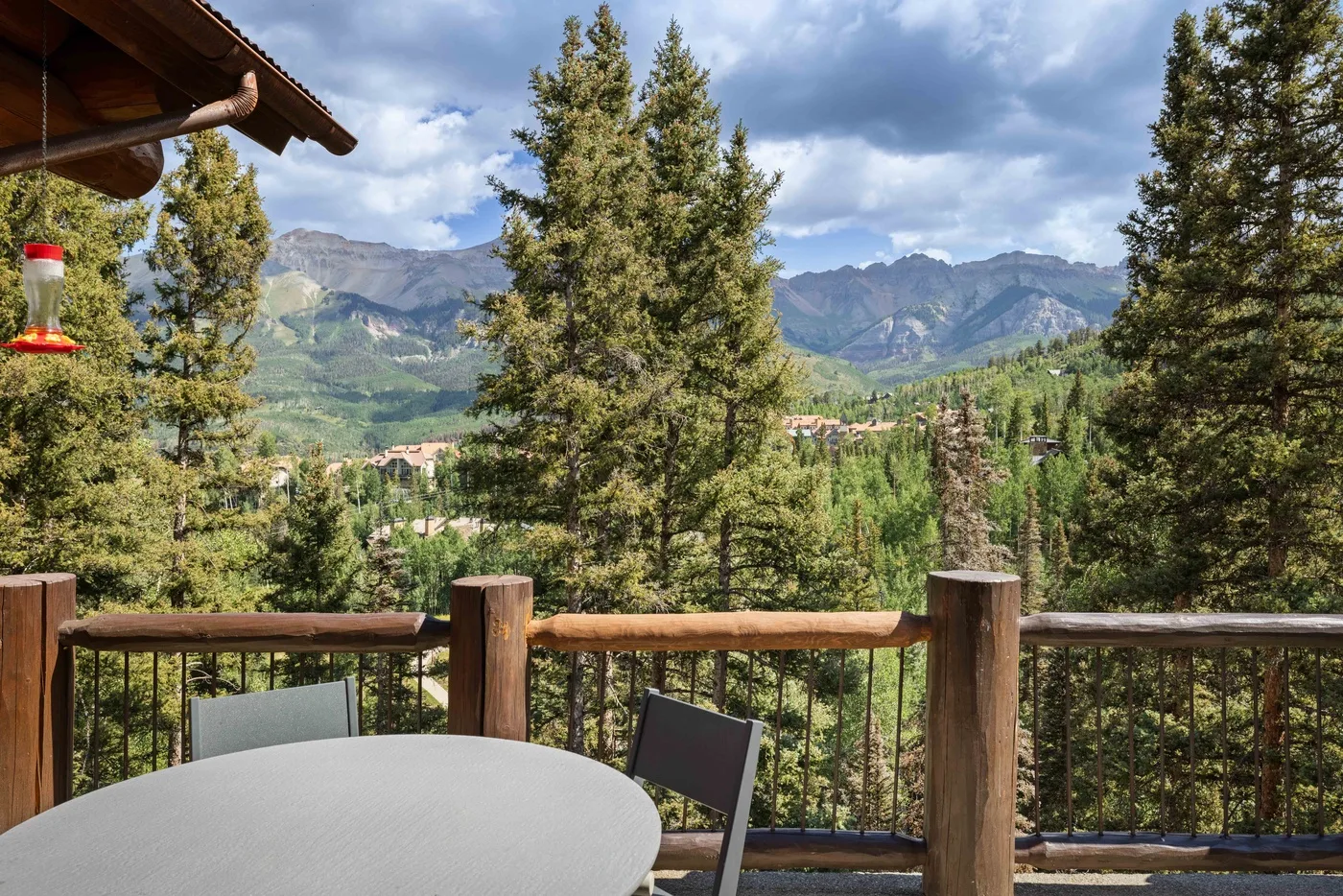 A balcony seating area overlooks trees and a mountain valley.