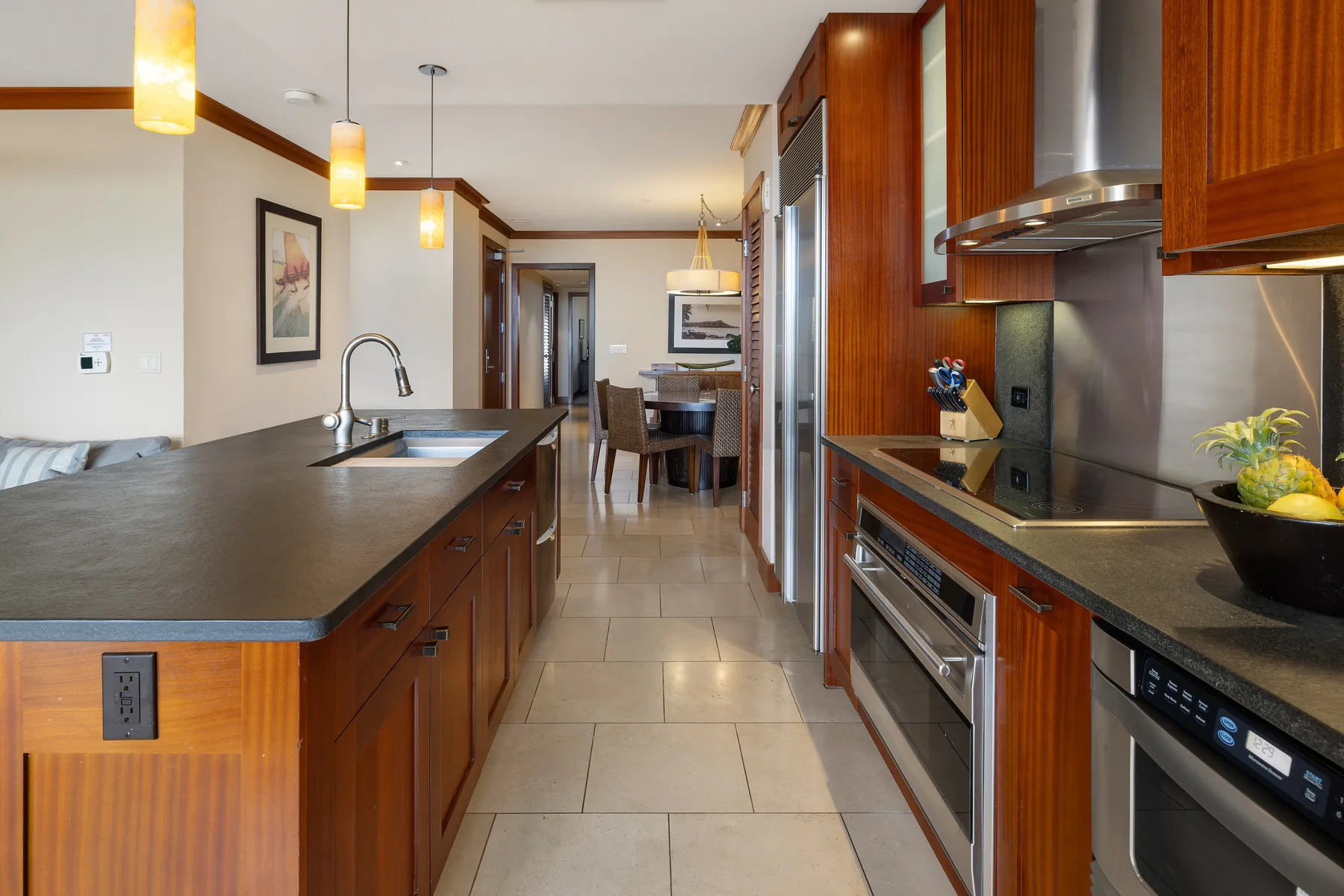 Una cocina moderna con una isla larga, fregadero y electrodomésticos de acero inoxidable.