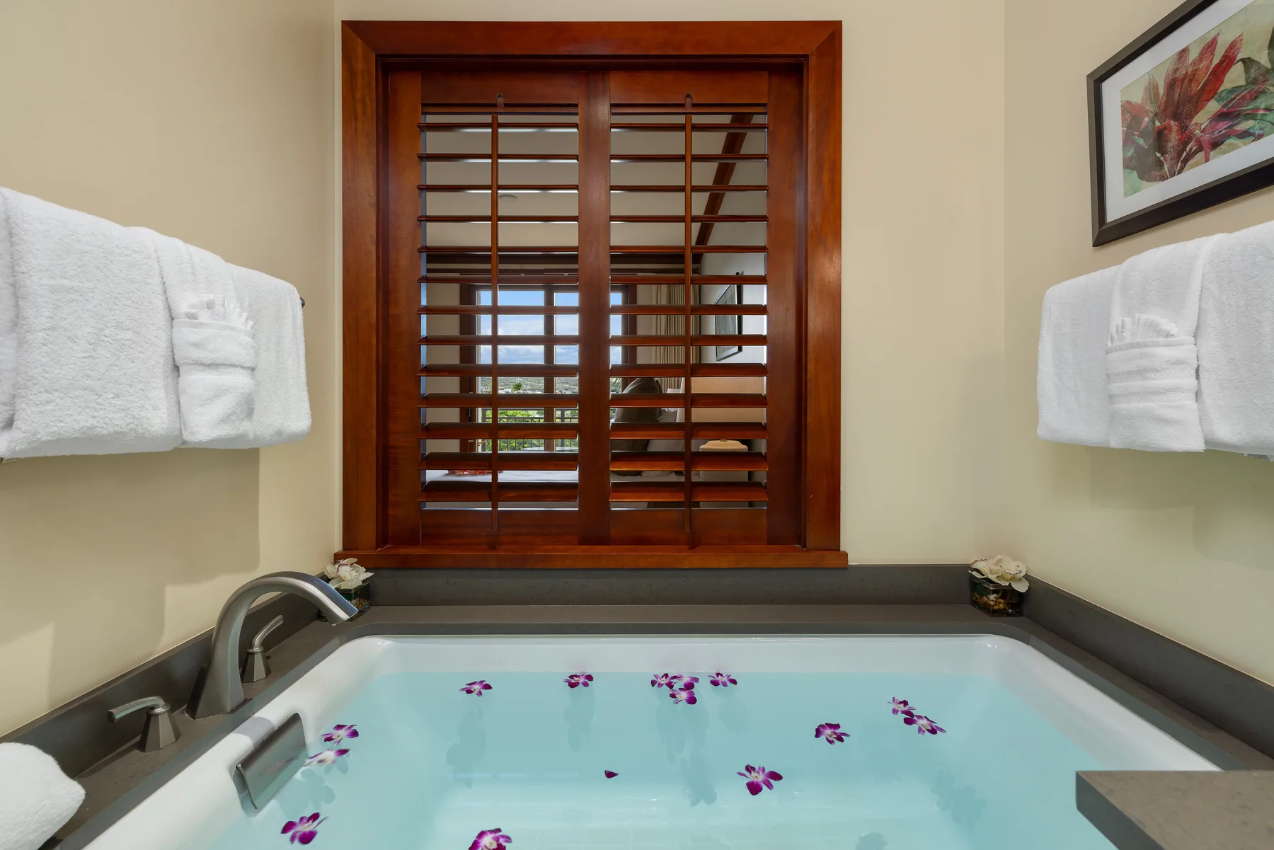 Un baño con una bañera amplia bajo una ventana de madera.