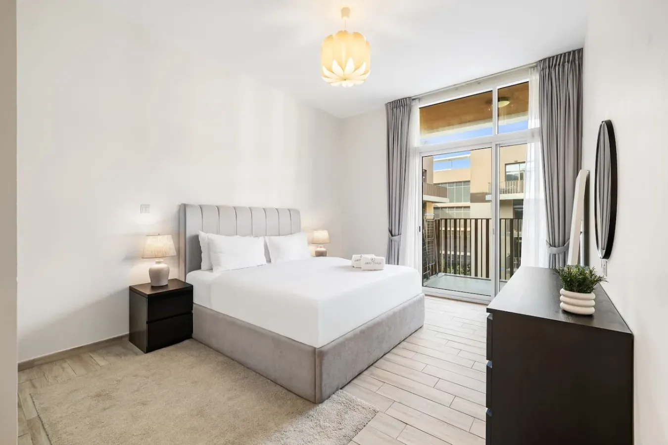 Un dormitorio luminoso con una cama grande junto a una ventana y una puerta de balcón.