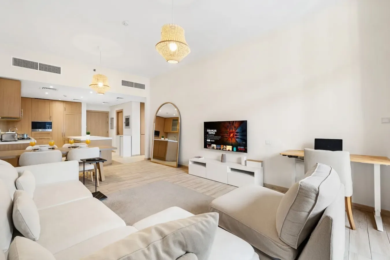 A bright living and dining area with pale seating and an open kitchen.