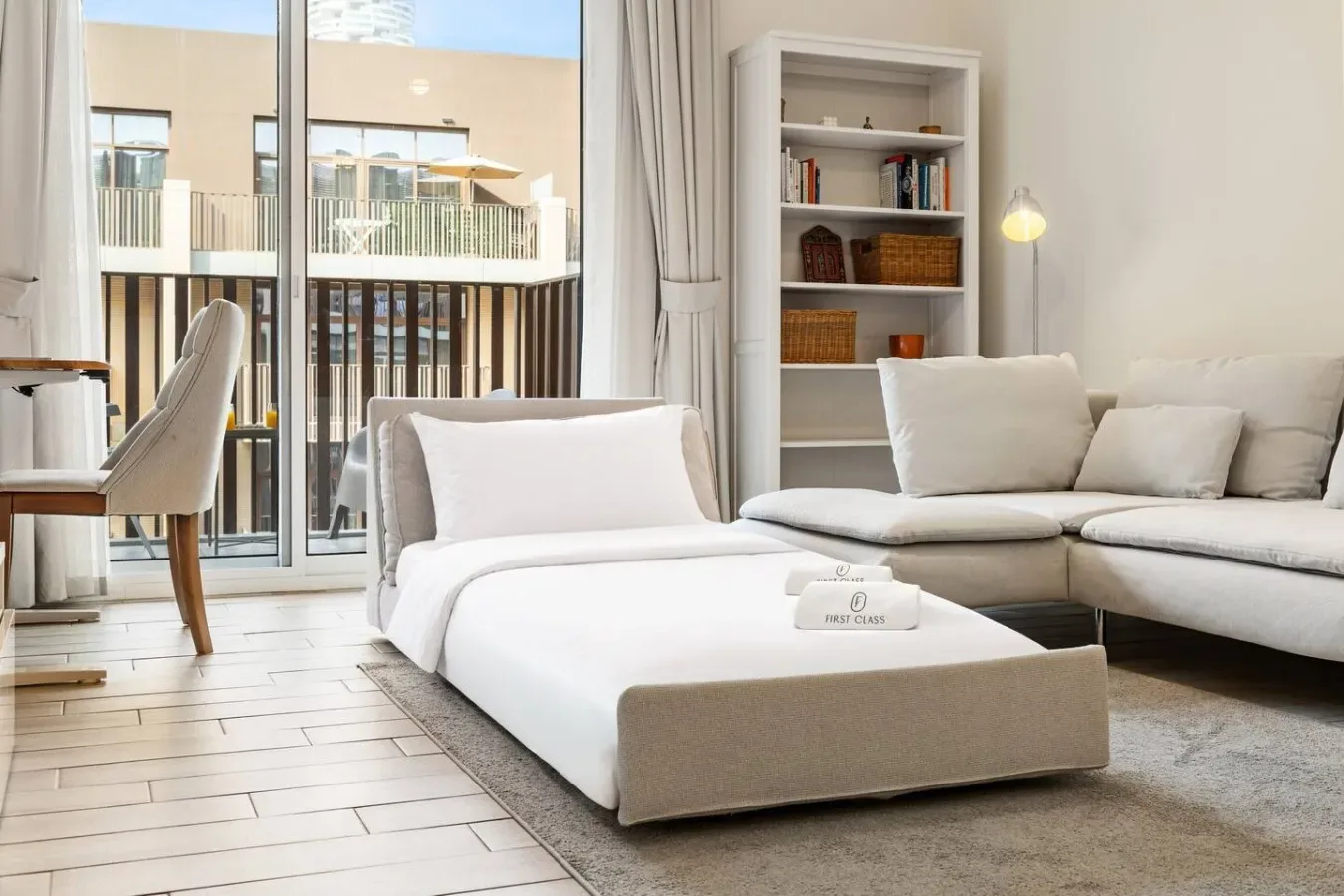 A bright living room with low white seating beside large glass doors.
