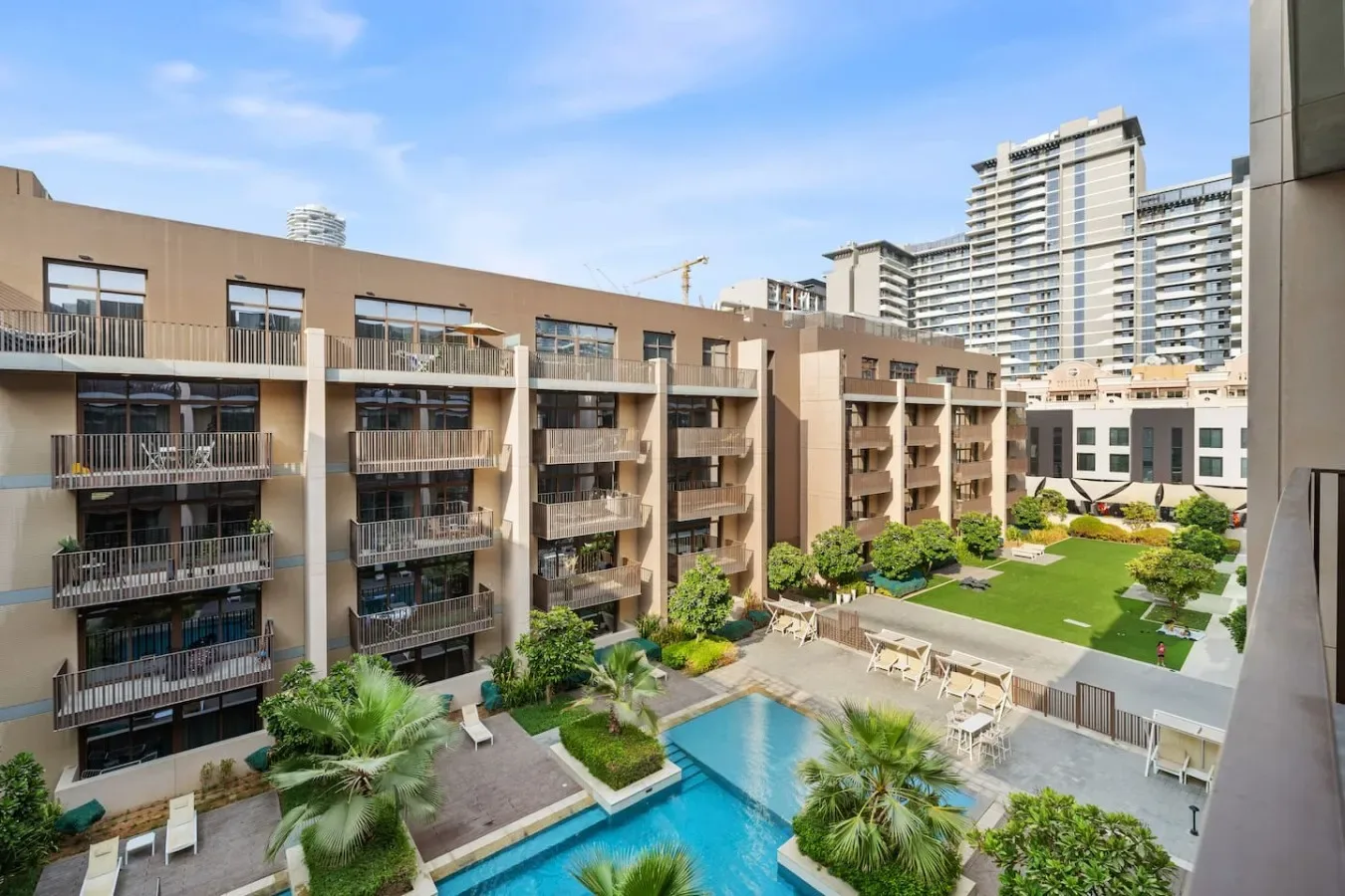 Apartment buildings overlook a landscaped courtyard with a swimming pool.