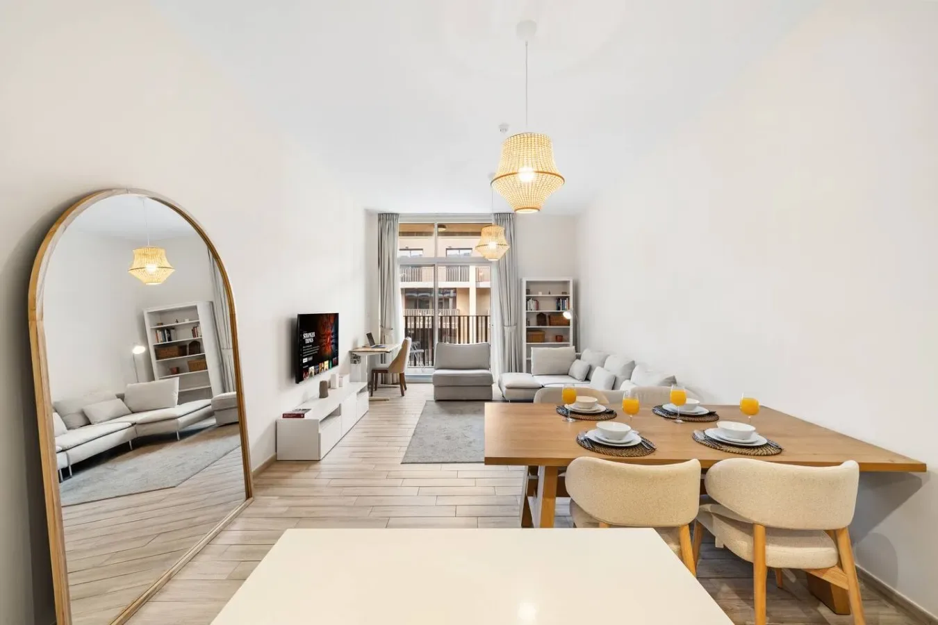 Una luminosa sala de estar y comedor con mesa, asientos y ventanas grandes.