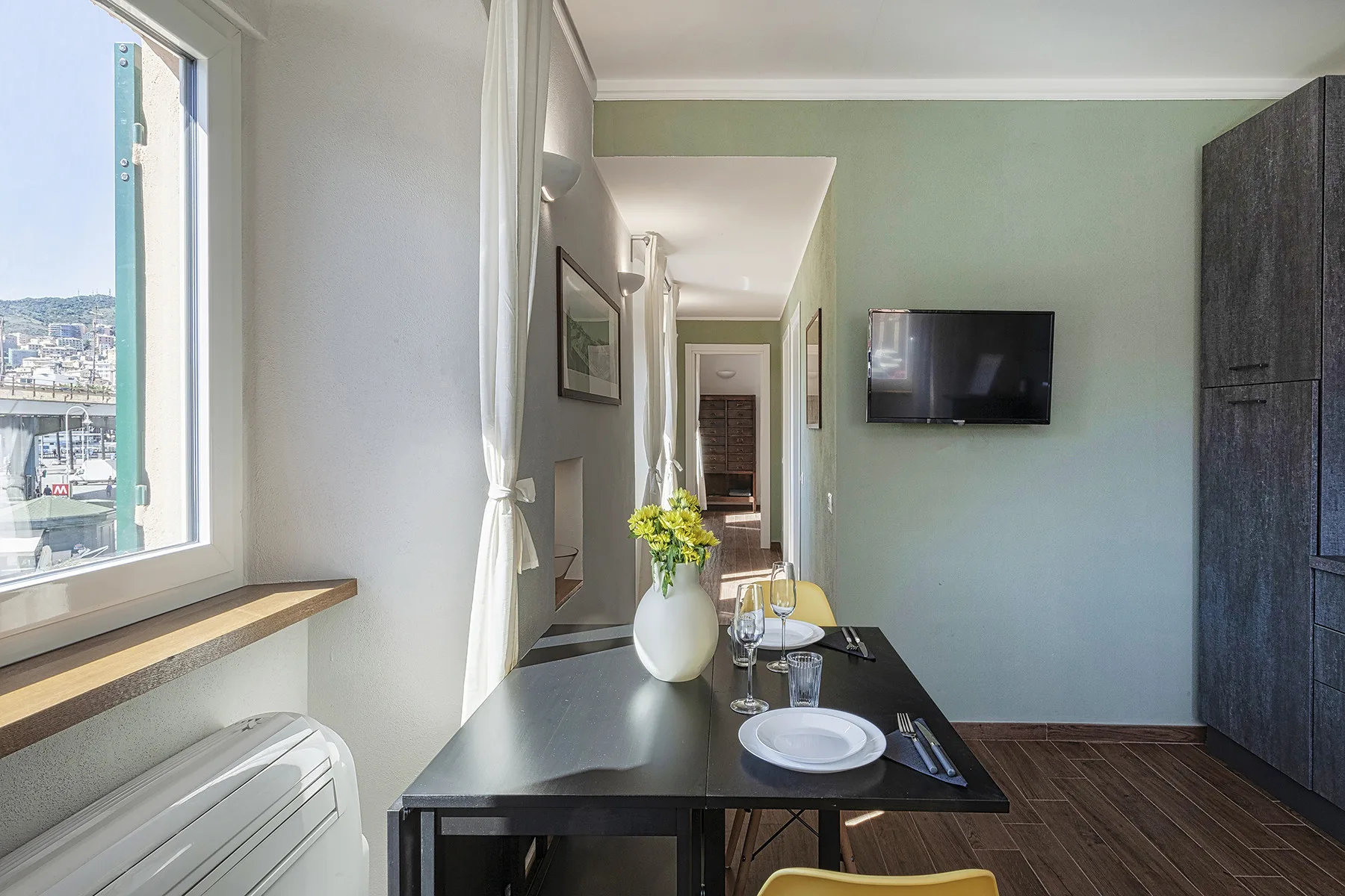 A dining area with a set table beside a large window.