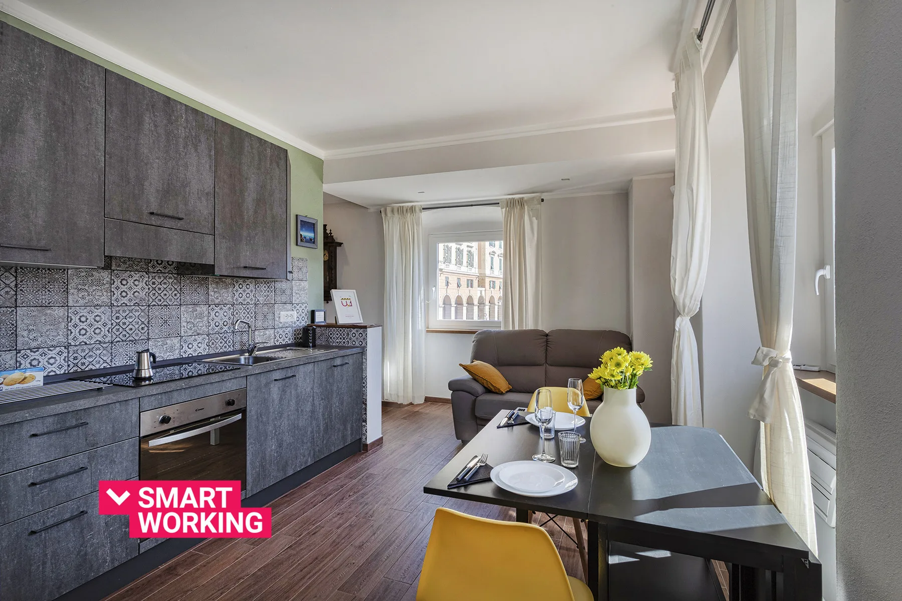 A kitchen and dining area with dark cabinetry, a table, and seating.